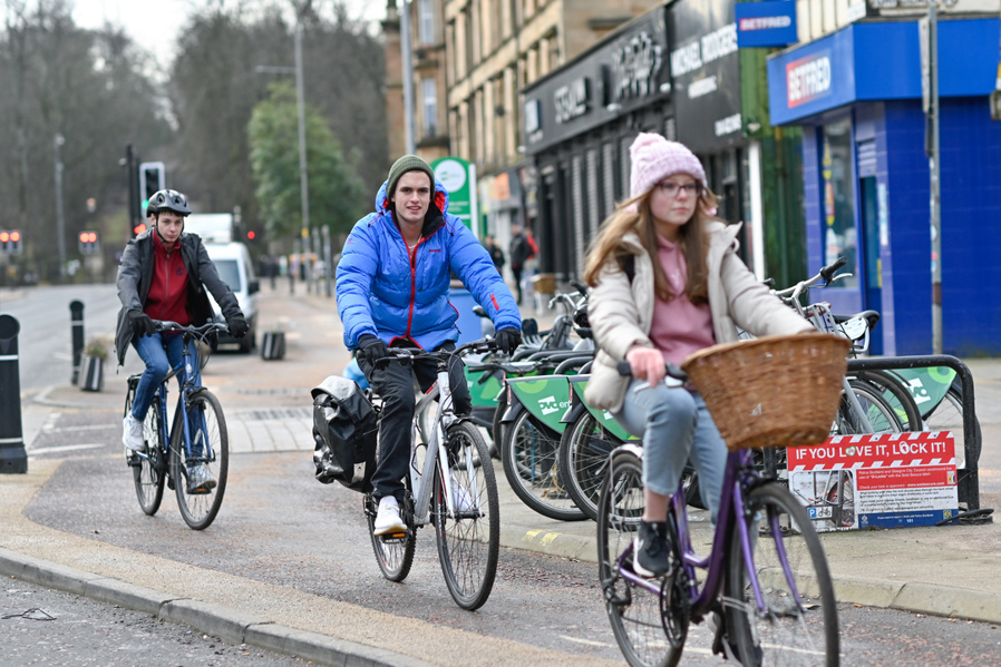 Three young people ride their bikes on the South City Way cycle route in the southside of Glasgow on a winter's day