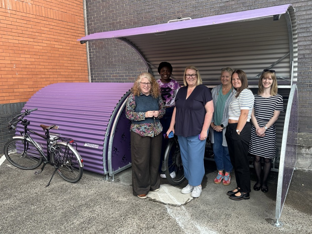 Staff at Key stand with their newly installed bike hangars, giving them a secure space to store their bikes at work