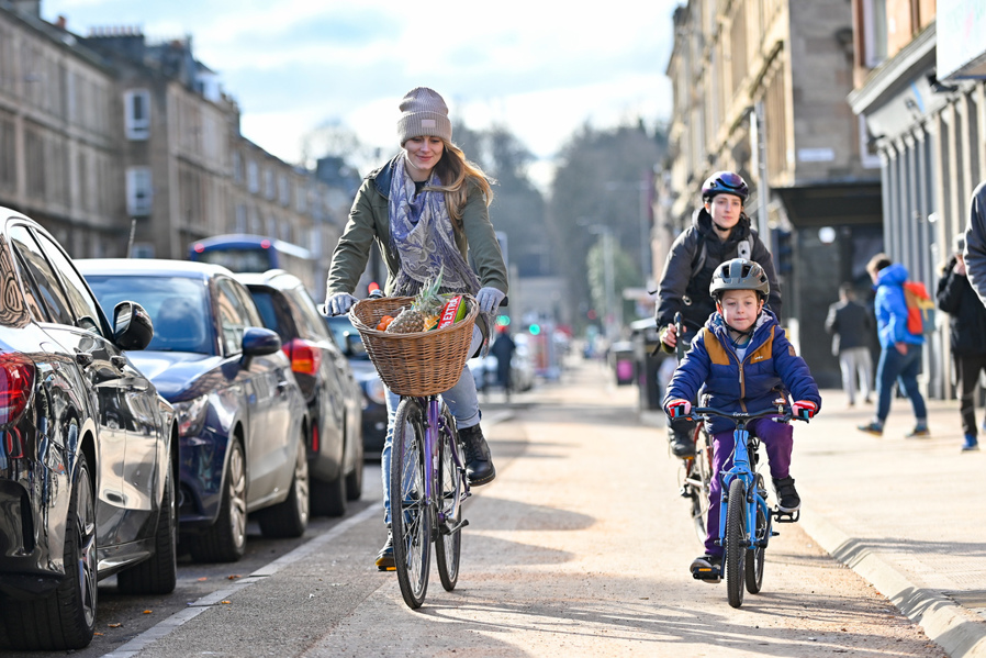 A woman and young child cycle together along the South City Way cycle route on Victoria Road, Glasgow