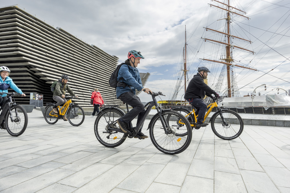 Cycling Scotland Conference delegates cycle past the V&A Dundee and the RRS Discovery at Dundee Waterfront