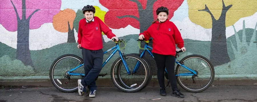 Two pupils from Ferryhill Primary School smile as they stand next to their bikes