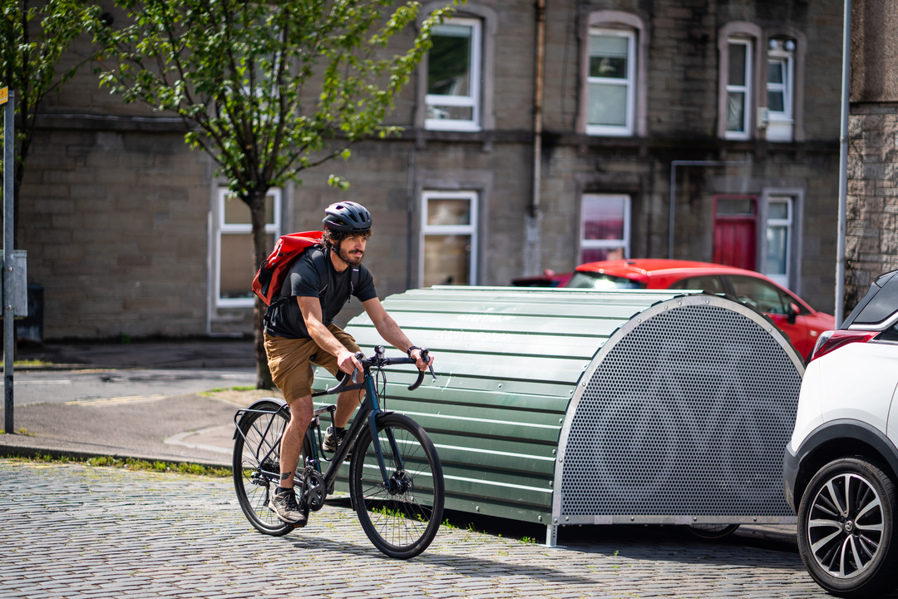 A local resident cycles past their cycle storage unit on a Dundee street