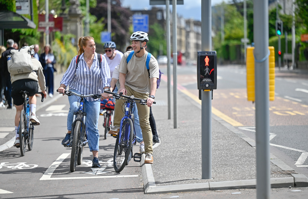 People smile and chat to one another as they cycle together on a protected cycle lane in Edinburgh