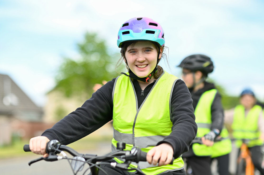 A girl smiles with her bike during a Bikeability Scotland cycle training session