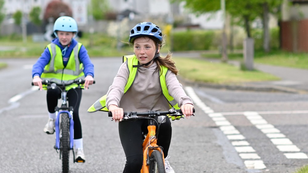 Schoolchildren ride their bikes on a residential street during Level 2 on-road Bikeability Scotland cycle training
