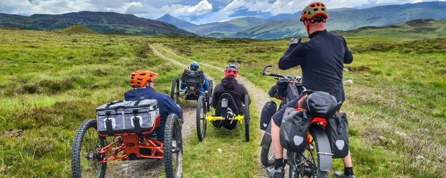 The Adaptive Riders Collective, cycling along a rural path in Loch Lomond and the Trossachs National Park