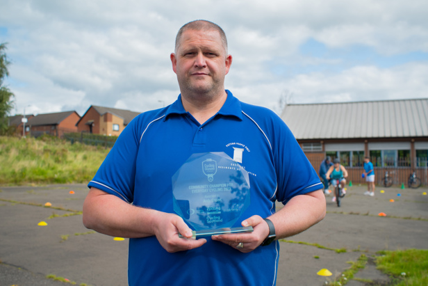 Man in playground holding glass award