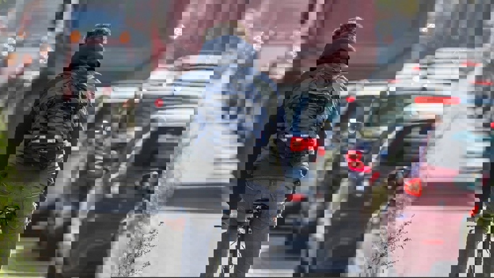 Photo of a man cycling in a non-protected cycle lane, next to heavy vehicle traffic