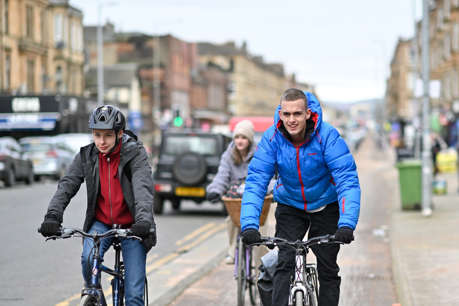 Three young people cycle on the South City Way cycle route in Glasgow