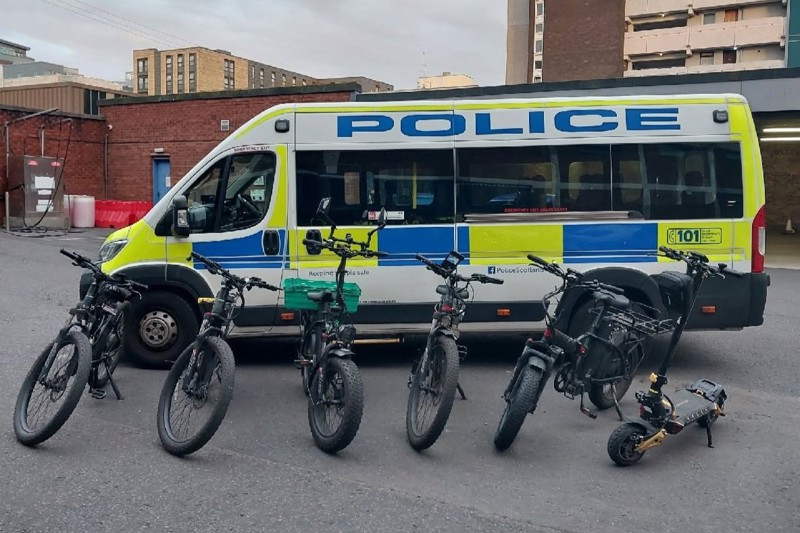 Illegally modified e-bikes which have been confiscated by the police, stand next to a Police Scotland van