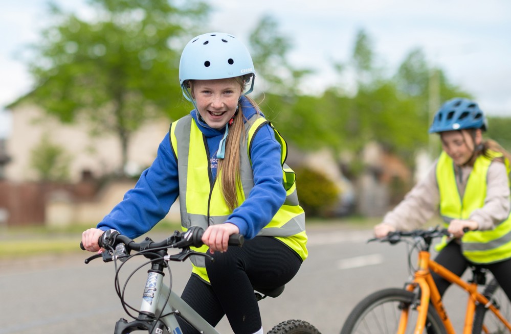A girl smiles as she rides her bike during Bikeability Scotland cycle training