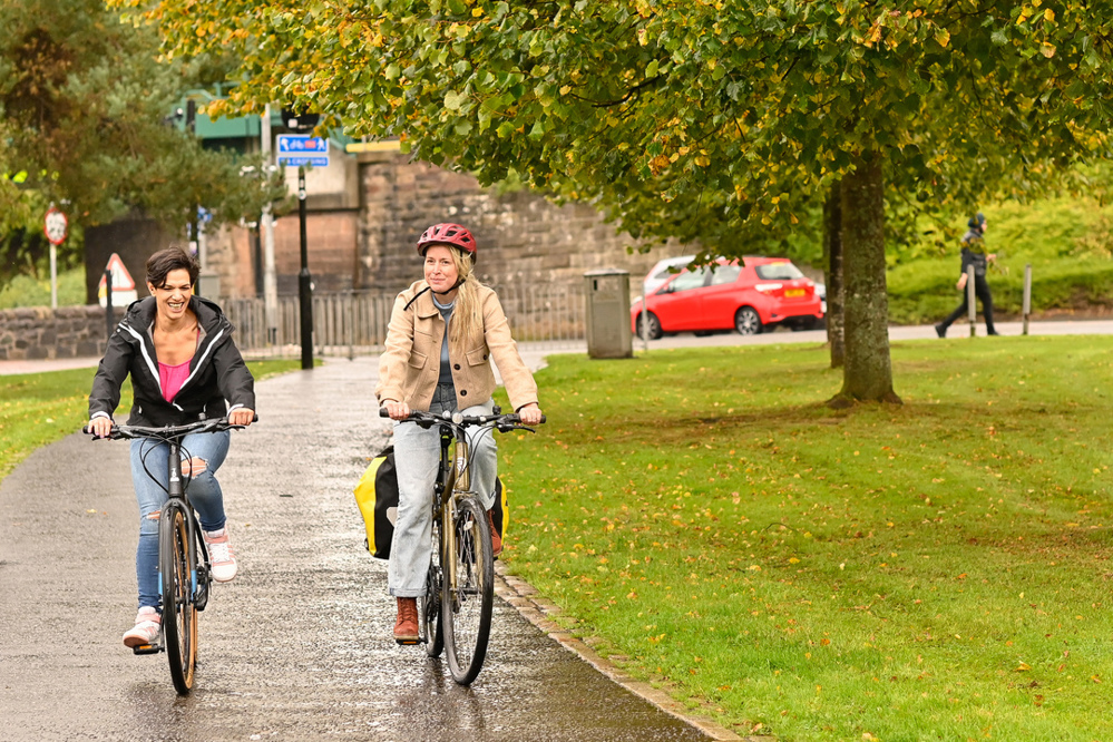 Two women cycle together on a shared use path in Stirling