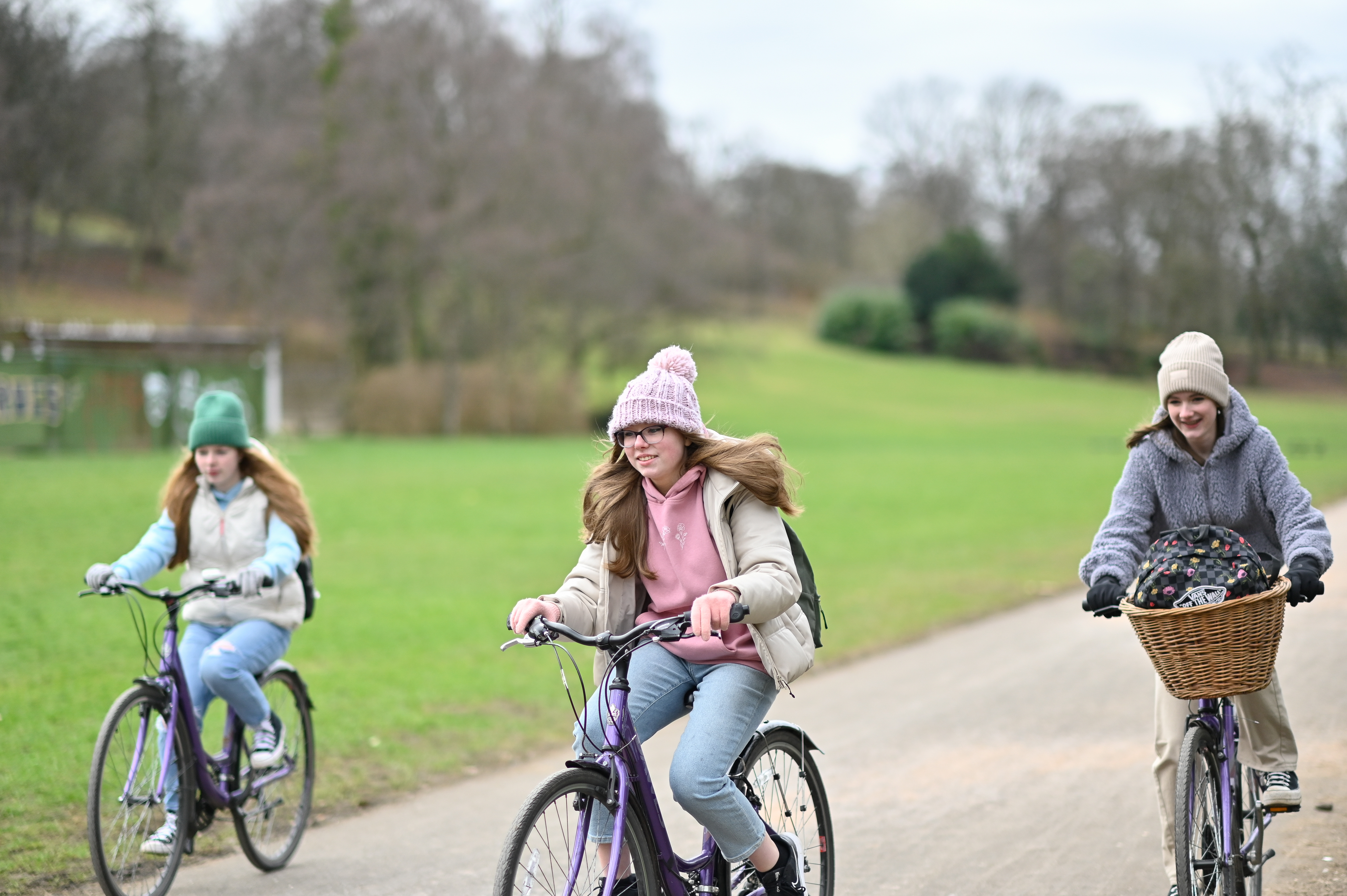Three young girls cycling socially in the park